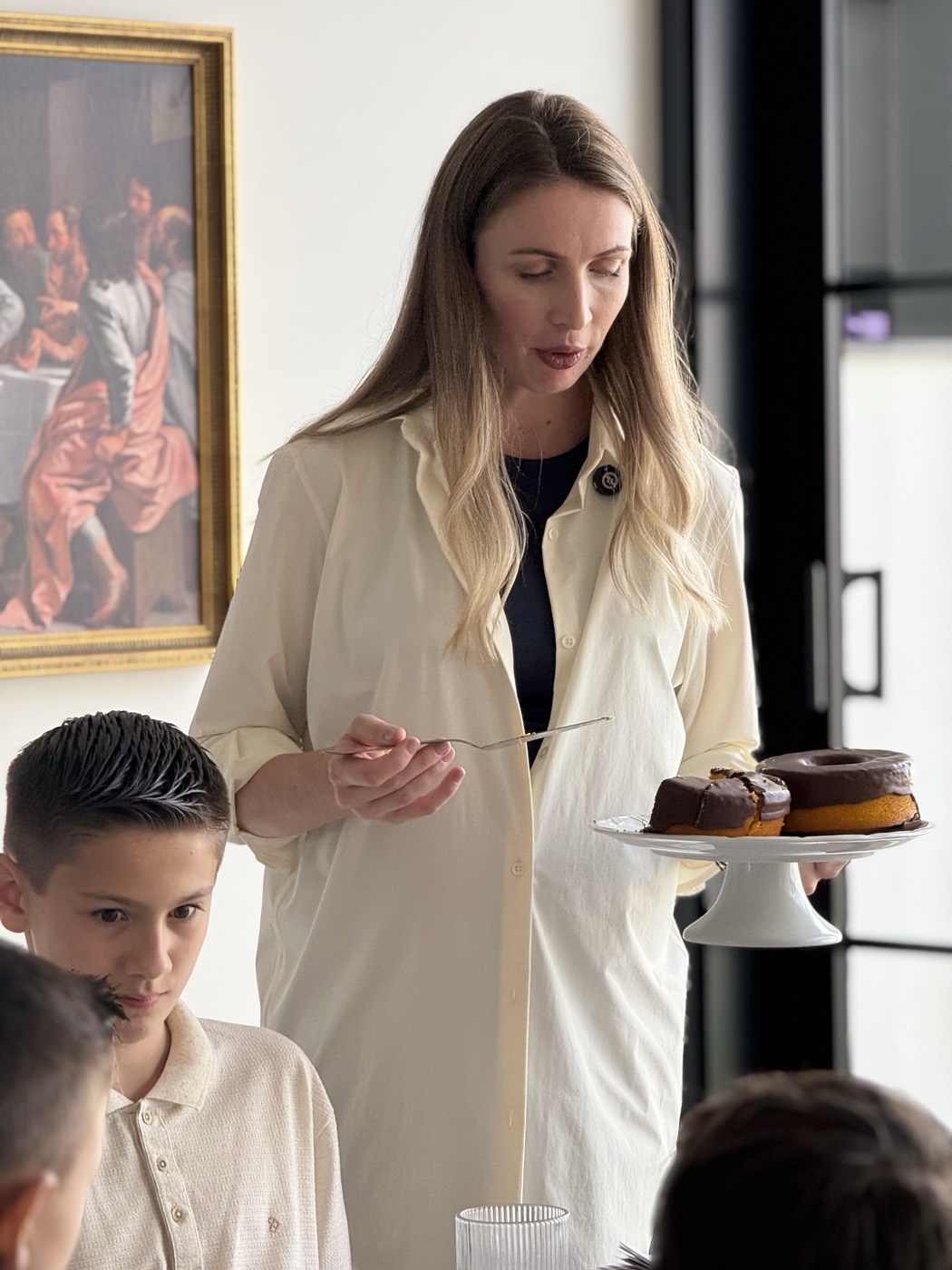 Caroline Berri servindo um bolo em casa, luz natural.